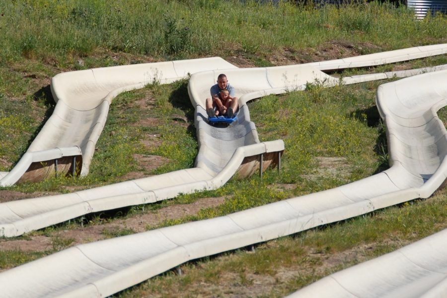 A rider on a blue sled coming down a zigzag alpine slide course
